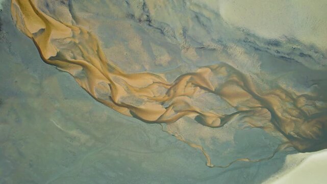Aerial view of abstract sand formations and sediment flowing through shallow coastal waters near Kingfisher Bay Resort on K'gari, Queensland, Australia.