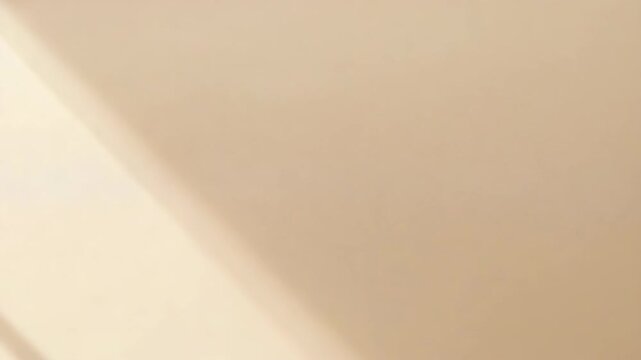 Beige wall with diagonal sunlight and shadow creating warm minimalist mood with soft window shadows