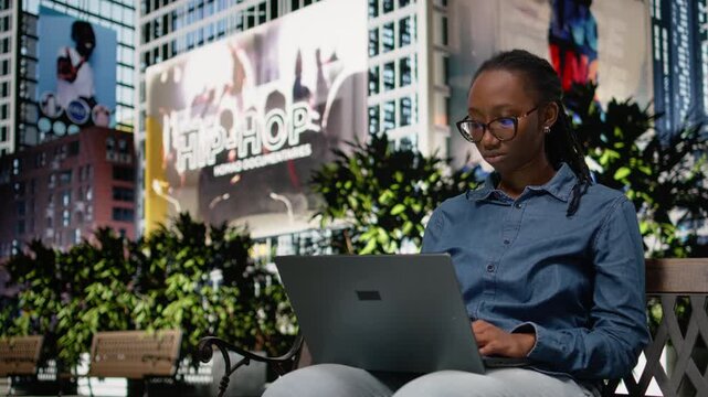 Concerned black woman struggling to meet deadlines with laptop, upset digital nomad working on bench in the park. Worried remote employee outside feeling overworked, dissatisfaction.