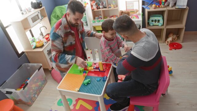 Man guiding little boy stacking colorful building blocks on a play table in a building; playful family bonding.