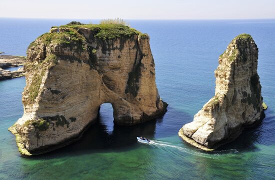 Excursion boat off the Pigeons Rock, Grotte aux Pigeons, limestone rocks eroded by wind and weather in the Raouche district, Beirut, Lebanon, Middle East, Asia