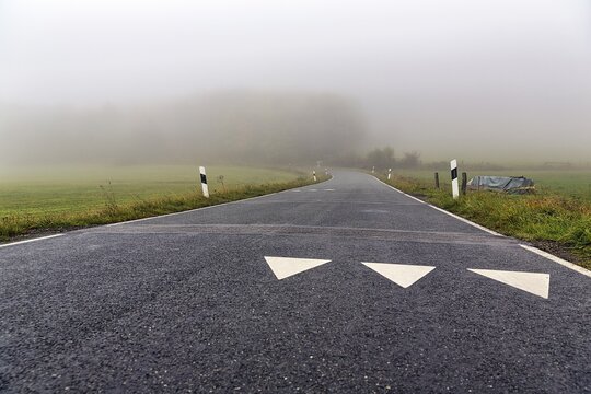 White triangles on roadway, shark's teeth, speed limit markings, winding road to K&ouml;terberg, dreary autumn weather with fog, L&uuml;gde, Weserbergland, North Rhine-Westphalia, Germany