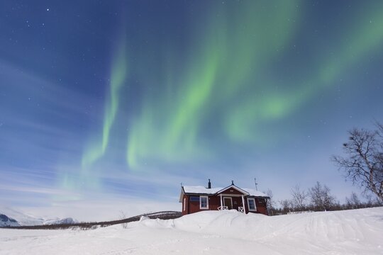 Northern Lights (Aurora borealis) above a Swedish red house in winter, Kungsleden, Province of Lapland, Sweden