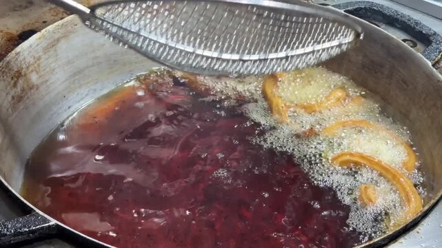 Chef deep frying churros in boiling oil