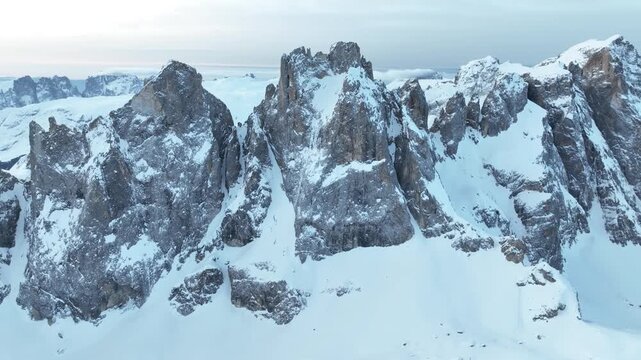 Aerial view of the snow-covered Parco Naturale Paneveggio Pale di San Martino peaks with jagged rocky cliffs in Primiero San Martino di Castrozza, Trentino-Alto Adige, Italy.