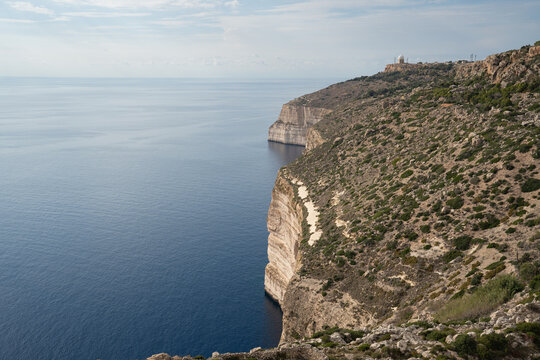Epic Malta Dingli cliffs coastal rock landscape panorama. 
Cinematic view of historic limestone cliffs, 
deep blue mediterranean sea water and scenic sunset clouds sky.
