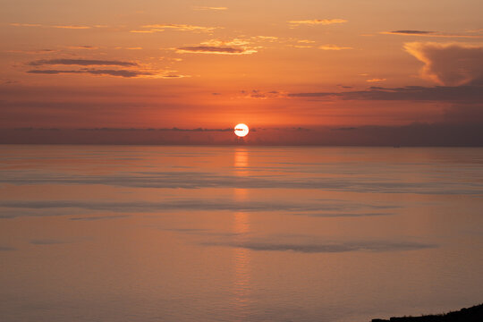 Epic Mediterranean sea sunset panorama. 
Cinematic ground view of golden sun 
setting down over calm ocean horizon.
