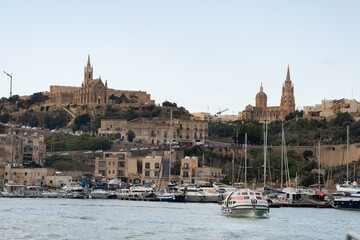 Fototapeta premium Horizontal scenic view of ancient neo-gothic church on rocky hill. Majestic old limestone cathedral architecture background in Gozo island, Malta. 