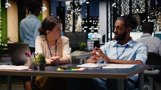 Cheerful coworkers doing fist bump pleased by business results, middle eastern man in wheelchair celebrating task success with his manager. Disability friendly office workspace late at night.