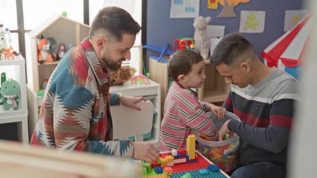 Man and little boy sort colorful blocks, hands reaching into a plastic bucket in a building playroom; family bonding playful.