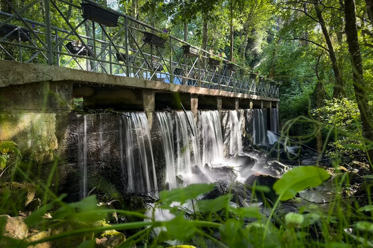 Small waterfall and pedestrian bridge with flower pots at Parque de Lazer da Varzea in Santa Maria da Feira Portugal