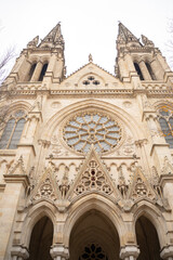 Obraz premium Symmetric vertical view of gothic cathedral facade. Ancient neo-gothic church with stone rose window and towers. Epic historic architecture background in Bordeaux, France. 