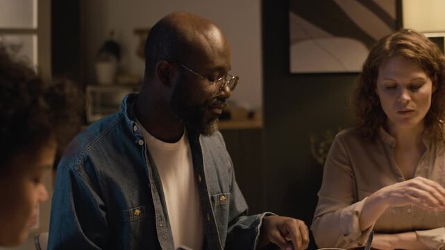 Candid close up shot of Black man as stern father slamming hand on dinner table and telling off son using smartphone during dinner, boy leaving room, copy space
