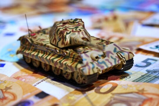 Toy tank on euro banknotes symbolizing military spending and defense budget in Europe