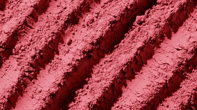 From-above capture of red powder furrows surface highlighted by moving directional light casting dynamic shadows | Creative concept for a blush commercial