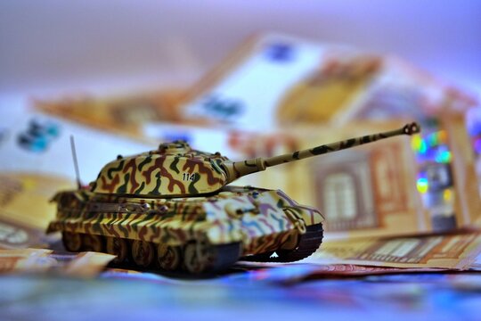 Toy tank on euro banknotes symbolizing military spending and defense budget in Europe