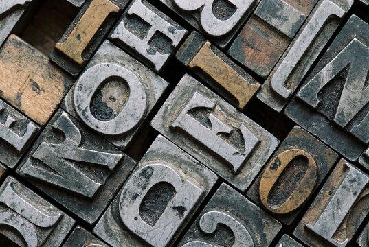 Macro Close Up of Assorted Vintage Metal Letterpress Type Blocks with Weathered Patina Showing Mixed Alphabet Letters in Diagonal Arrangement