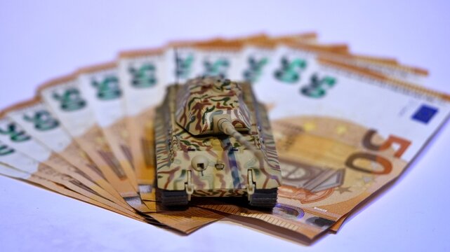 Toy tank on euro banknotes symbolizing military spending and defense budget in Europe