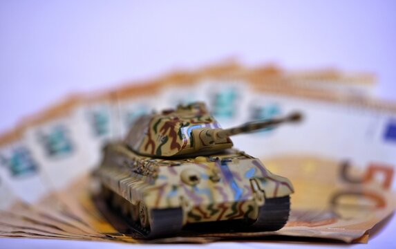 Toy tank on euro banknotes symbolizing military spending and defense budget in Europe