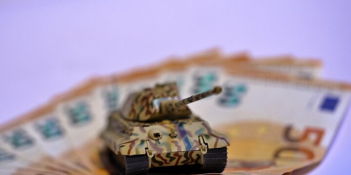 Toy tank on euro banknotes symbolizing military spending and defense budget in Europe