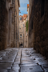 Obraz premium Epic traditional old town narrow street ancient architecture vertical panorama. Cinematic view of historic medieval limestone house facades, wooden window shutters, vintage iron lantern and cozy all