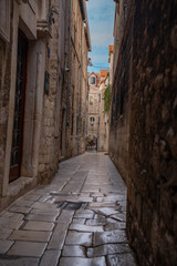 Fototapeta premium Epic traditional old town narrow street ancient architecture vertical panorama. Cinematic view of historic medieval limestone house facades, wooden window shutters, vintage iron lantern and cozy all