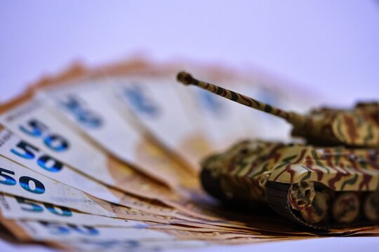 Toy tank on euro banknotes symbolizing military spending and defense budget in Europe