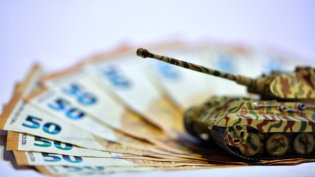 Toy tank on euro banknotes symbolizing military spending and defense budget in Europe