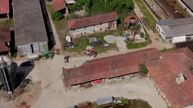 Rural Farmstead Aerial View: An aerial perspective reveals a sprawling rural farmstead with agricultural buildings, tractors, and silos.