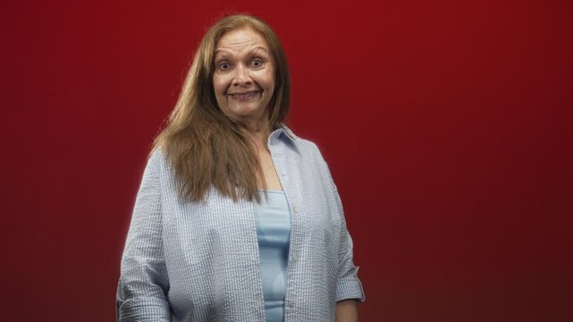 Woman with long hair turns head to side showing smiling face and blue blouse in studio; cheerful curiosity.
