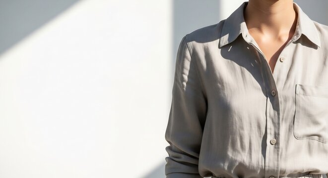 Minimalist Woman in Gray Button Shirt Standing by Sunlit White Wall