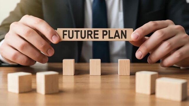 Future Plan in Hand: A businessman carefully holds a wooden block with FUTURE PLAN inscribed, surrounded by other blocks, symbolizing strategic thinking and forward planning in the business world.