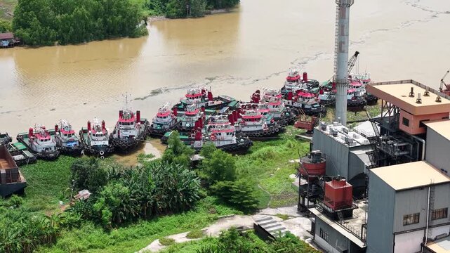 Aerial view of tugboats parked in a row on the riverbank next to barges
