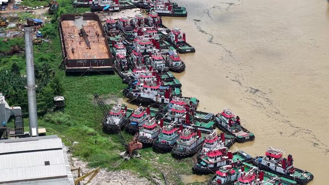 Aerial view of tugboats parked in a row on the riverbank next to barges