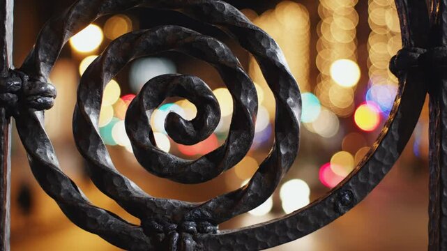 Intricate wrought iron spiral design in a gate with blurred bokeh lights creating a festive atmosphere in the background