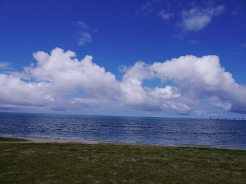 Green coastal lawn overlooking blue ocean with 
white clouds, Senaga Island, Tomigusuku, Okinawa, Japan