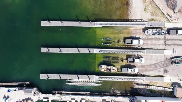 Overhead shot of a boat launch area with several trucks towing trailers. One boat was slowing being launched into the water. 