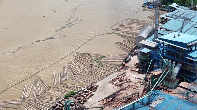 Aerial view of a plywood factory with stacks of logs in front of it as raw material for plywood production