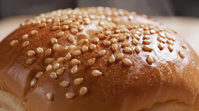 Closeup of a Golden Brown Bread Roll Topped with Sesame Seeds.