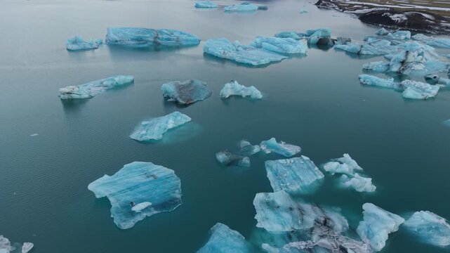 Aerial view of blue icebergs floating in the Jokulsarlon Glacier Lagoon with dark sediment streaks Sveitarfelagid Hornafjordur, Iceland.