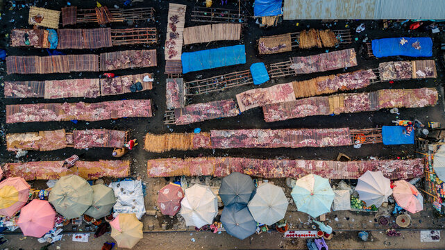 Aerial view of Panteka Market with colorful umbrellas, people, and goods displayed on wooden stalls and mats in Kaduna, Kaduna, Nigeria.