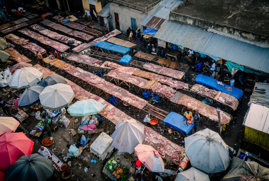Aerial view of Panteka Market showing rows of outdoor stalls with meat products, colorful umbrellas, and vendors in a busy trading area in Kaduna, Kaduna, Nigeria.