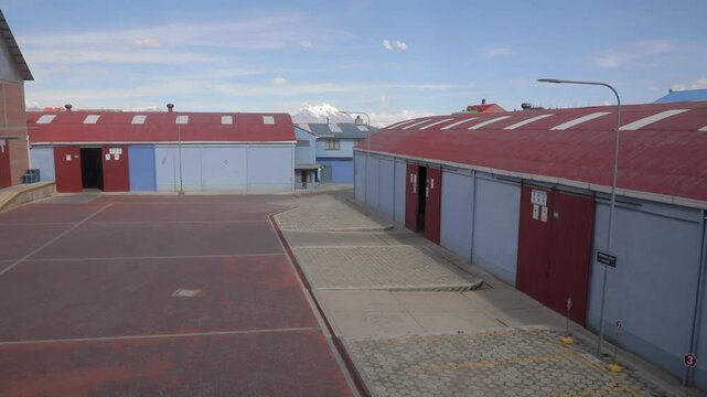 A large shed, with light blue walls and a red roof and doors, blends with the color of the sky on a sunny day. 