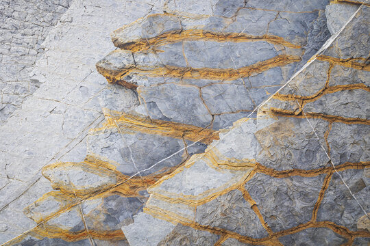 View of the unique geological rock formations with orange mineral veins at Playa de Sopelana in Vizcaya, Pais Vasco, Spain.