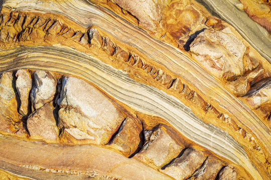 View of the intricate geological rock formations at Silence Beach with sedimentary layers and ochre mineral veins in Asturias, Asturias, Spain.