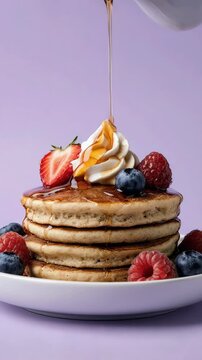 Golden syrup cascading over stacked pancakes topped with fruit cubes on a pastel background 