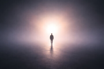 Fototapeta premium Silhouette of a person walking toward bright light in heavy fog concept.