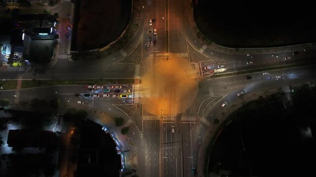 Vietnam, Da Nang Aerial Night Crossroads Da Nang Taxi Movement, Amber Glow Over Zebra Crossings, Lined Taxis And Scooters Easing Through Signal Changes, Reflective Asphalt And Scattered Neon