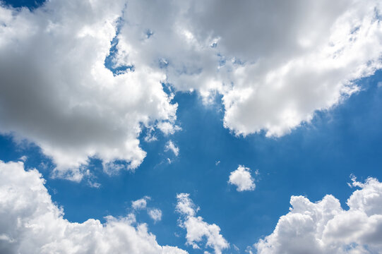 Bright Blue Sky with Fluffy White Clouds and Sunlight Peeking Through