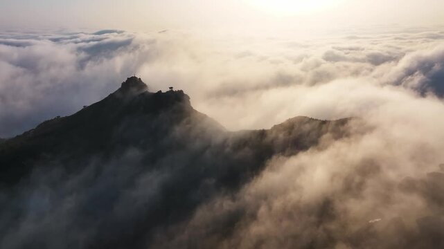 Mountain peaks emerging from a sea of clouds during sunrise with atmospheric light